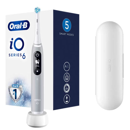Oral-B iO Series 6 electric toothbrush in grey, displayed next to a travel case and a fresh Ultimate Clean brush head on a clean white surface.