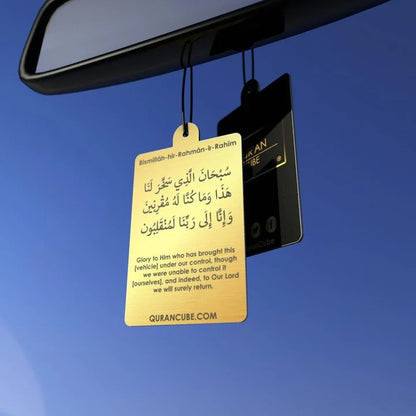 Quran Cube Oud fragrance hanging car air freshener card printed with Arabic Safar Dua script suspended against a dark car dashboard interior.