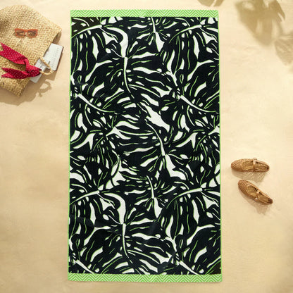 Flat lay view of the plush 500 GSM oversized 100 percent cotton jacquard beach towel spread out on golden sand.
