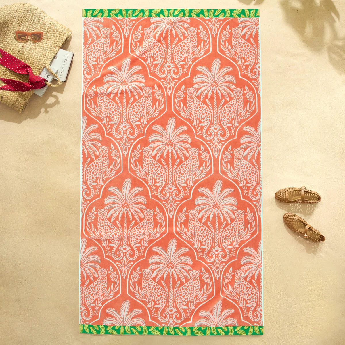Flat lay view of the plush 500 GSM oversized 100 percent cotton jacquard beach towel spread out on golden sand.