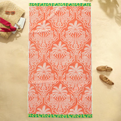 Flat lay view of the plush 500 GSM oversized 100 percent cotton jacquard beach towel spread out on golden sand.