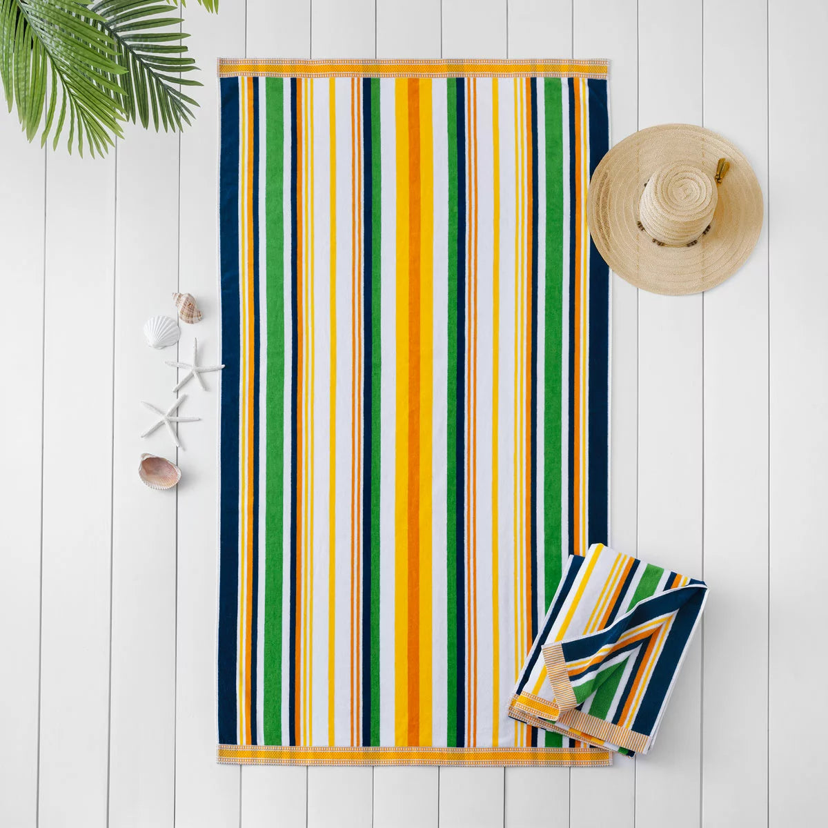 Flat lay view of the plush 500 GSM oversized 100 percent cotton jacquard beach towel spread out on golden sand.