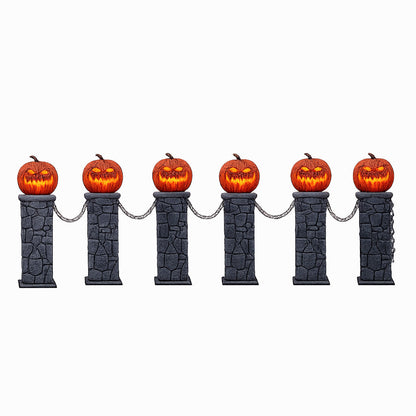 A set of two light-up Halloween pumpkin fences with grey aged-stone pedestals, lit orange jack-o'-lantern tops, and black plastic connecting chains positioned on a garden lawn at night.