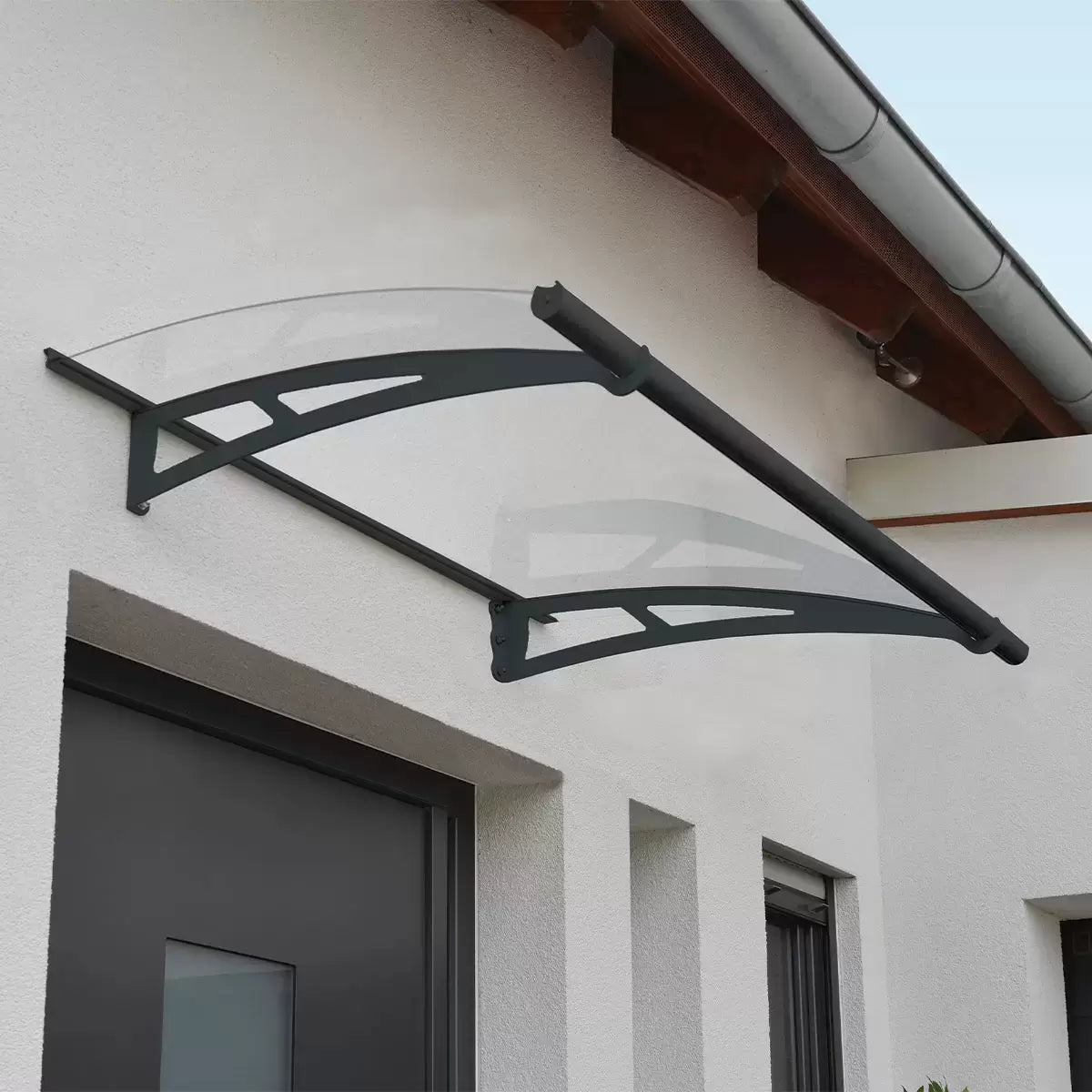 Palram Canopia Aquila clear polycarbonate door canopy with grey steel support brackets.