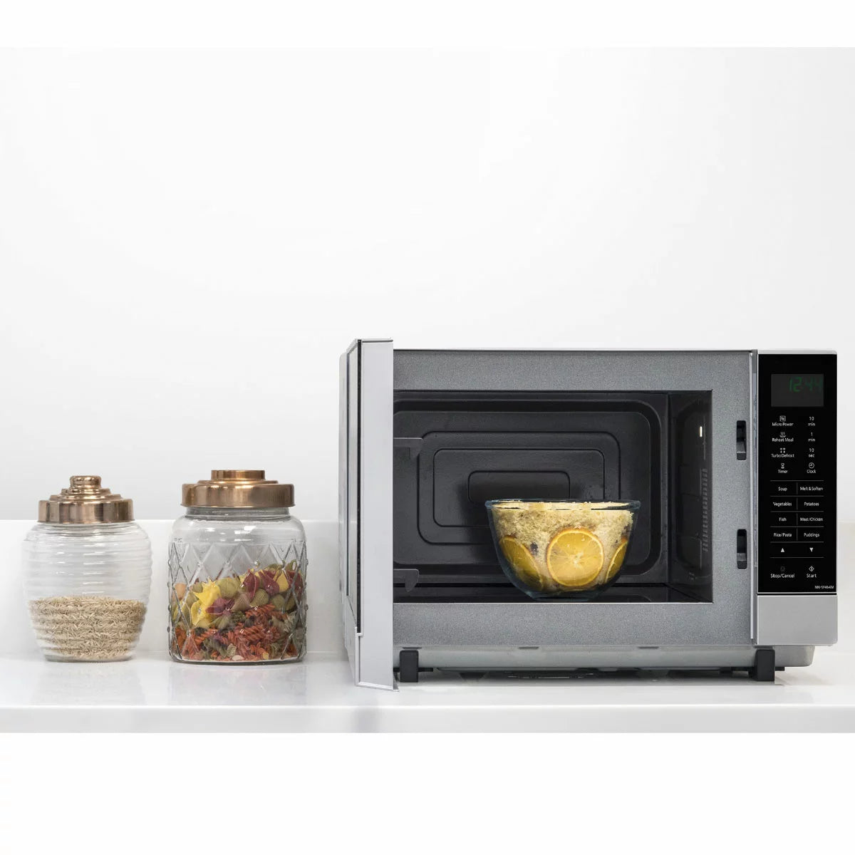 Panasonic NN-SF464MBPQ 27L flatbed microwave in silver, showing the mirror-effect door and spacious interior cavity, set on a modern white kitchen countertop.