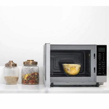 Panasonic NN-SF464MBPQ 27L flatbed microwave in silver, showing the mirror-effect door and spacious interior cavity, set on a modern white kitchen countertop.