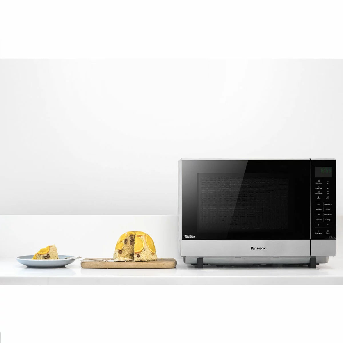 Panasonic NN-SF464MBPQ 27L flatbed microwave in silver, showing the mirror-effect door and spacious interior cavity, set on a modern white kitchen countertop.