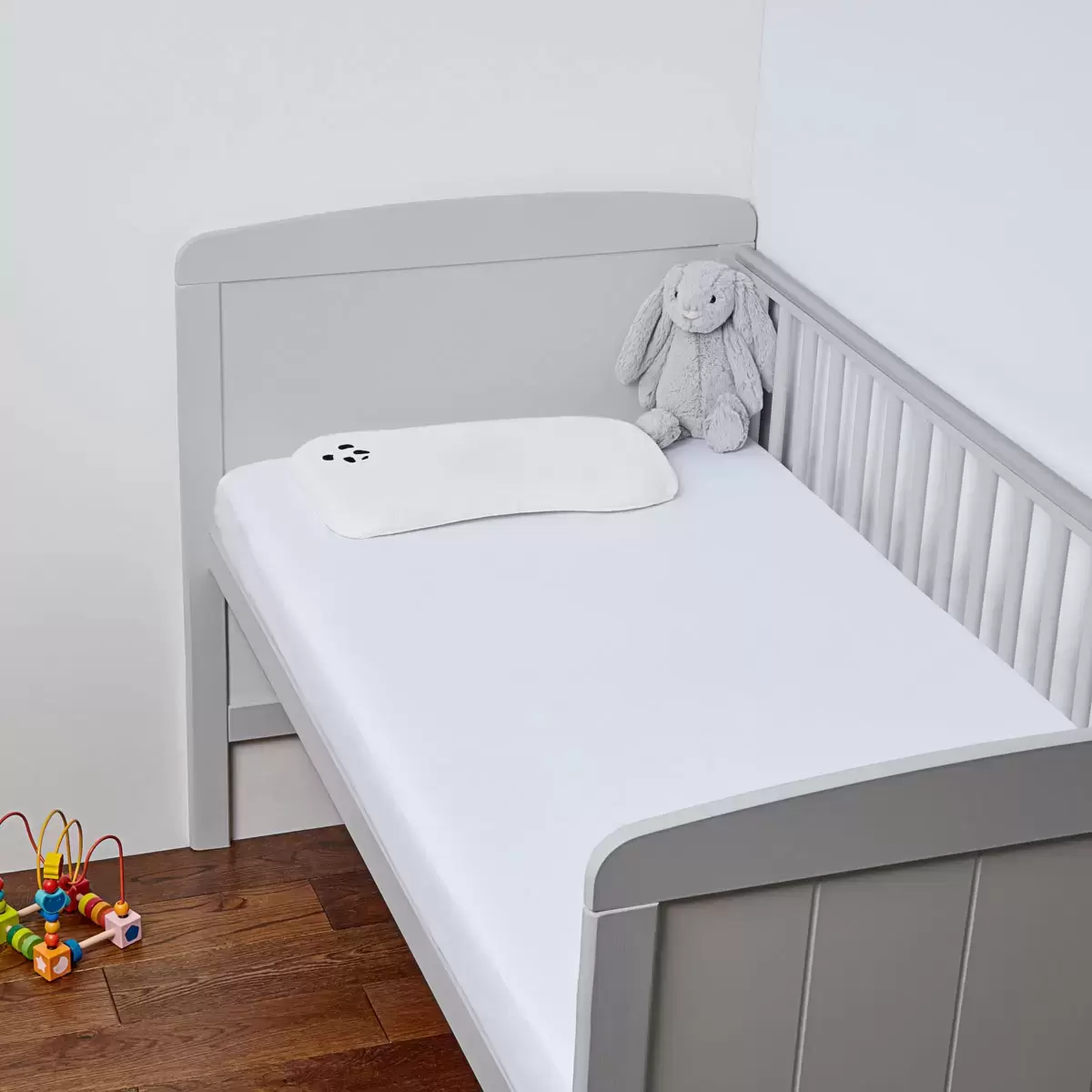 Close-up of the secure elasticated corner stitching on a white Panda bamboo fitted crib sheet.