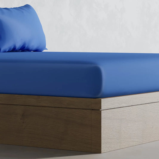 A close-up side angle of the deep navy Panda 100% bamboo fitted sheet pulled smoothly over a thick mattress corner in a minimalist bedroom environment.