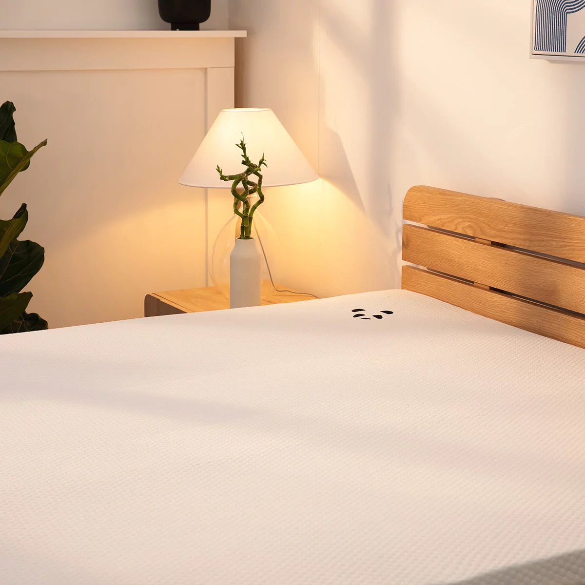 Corner view of the white Panda Memory Foam Bamboo Mattress Topper showing its textured bamboo zip cover, black anti-slip base, and elastic corner strap on a modern bed.