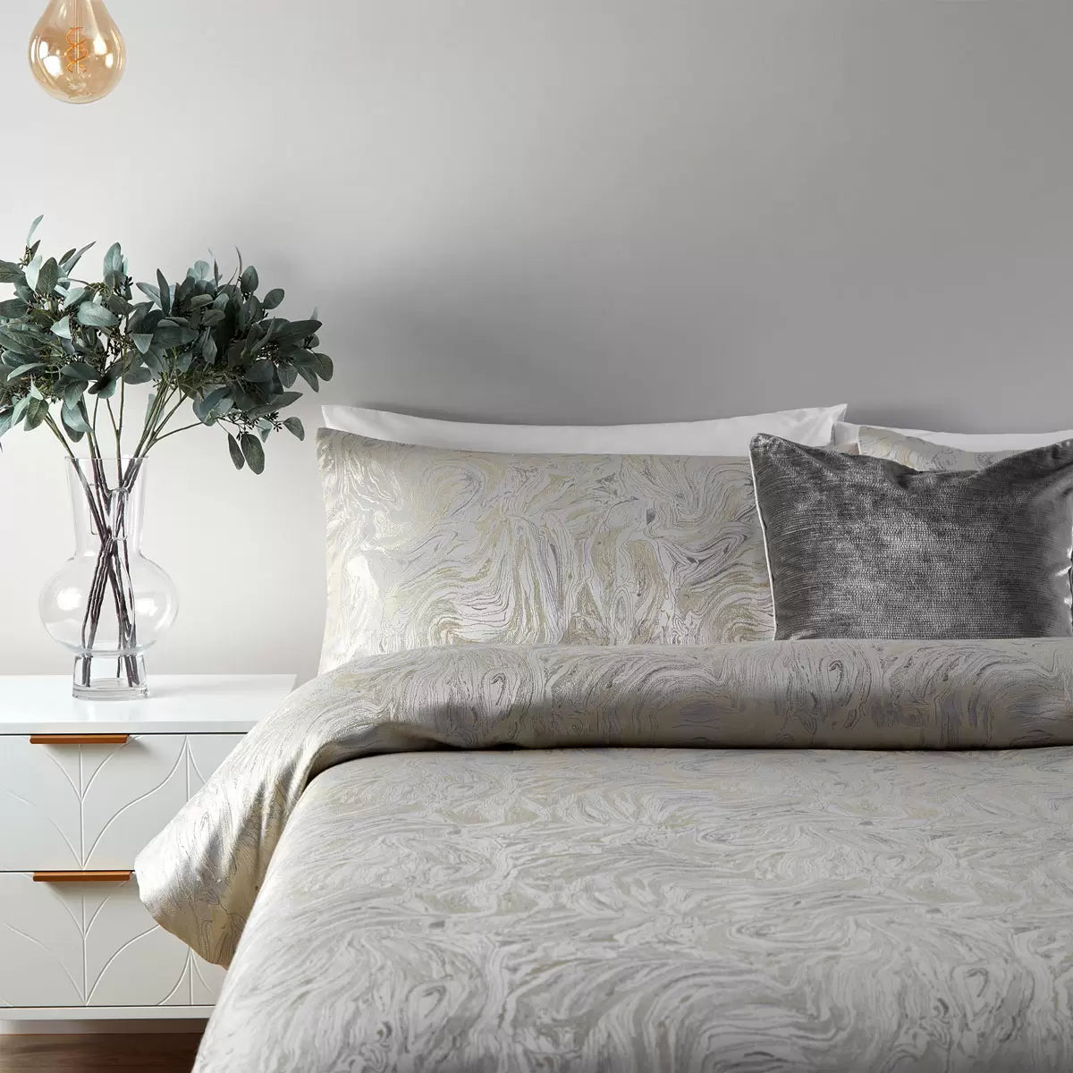 Neutral oyster Paoletti duvet cover displaying a metallic marble pattern on a bed with two matching pillowcases.