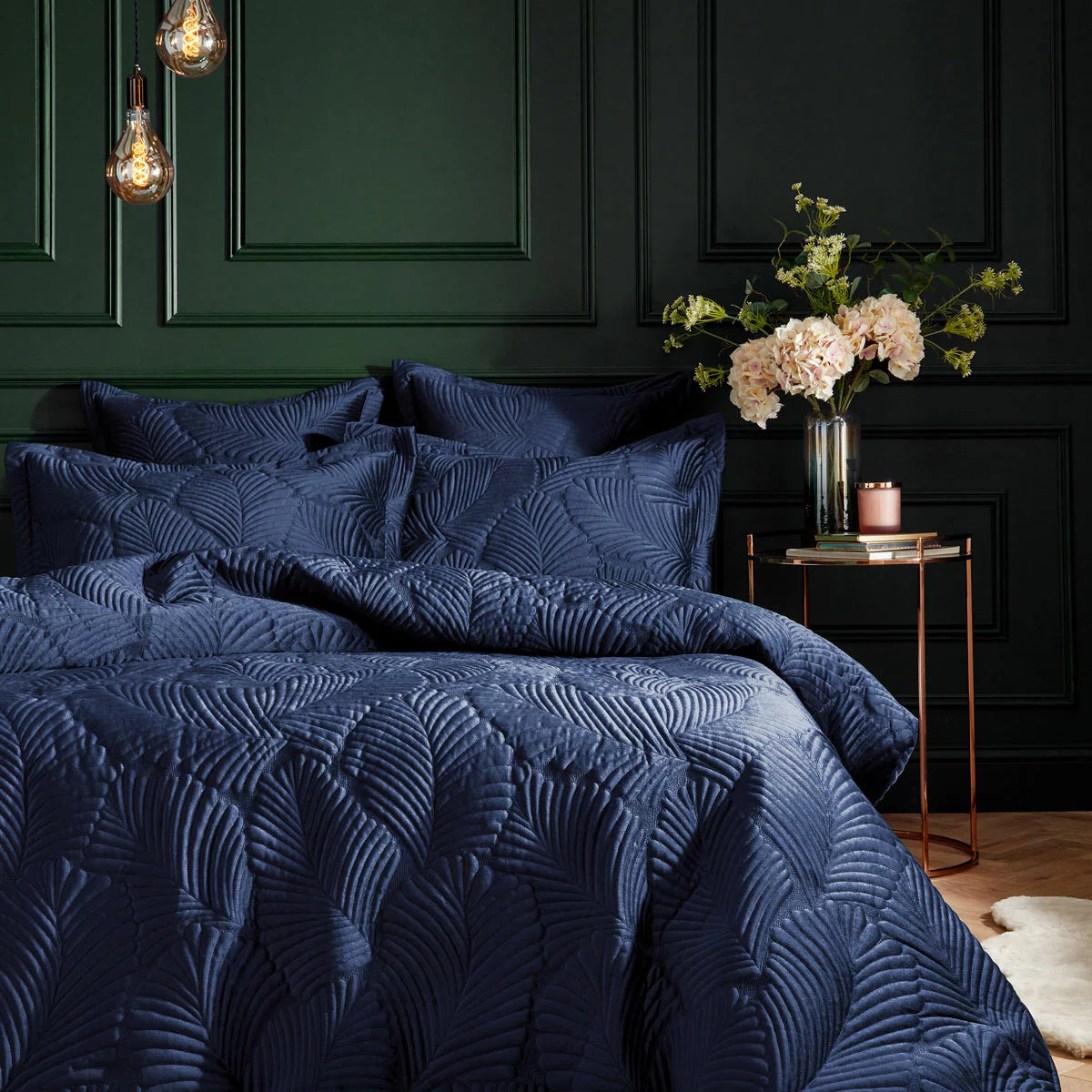 Deep navy blue Paoletti velvet duvet cover featuring gold palm embroidery with matching Oxford pillowcases styled on a modern bed.