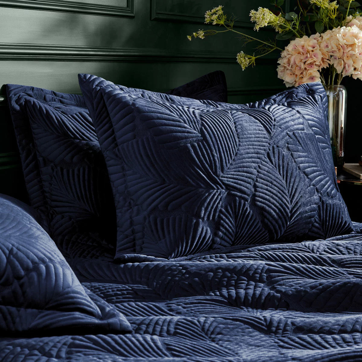 Deep navy blue Paoletti velvet duvet cover featuring gold palm embroidery with matching Oxford pillowcases styled on a modern bed.