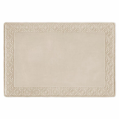 Top view of the Paramount taupe memory foam plush bath mat showing leaf-bordered stitched fabric and soft plush texture on a neutral tile floor.