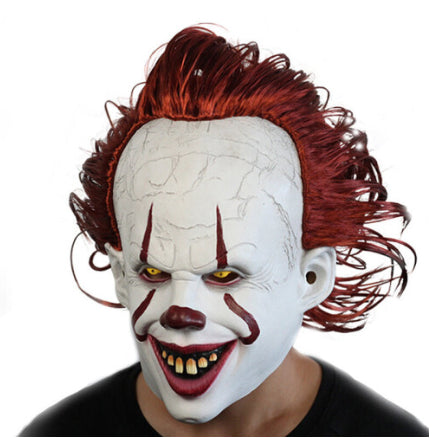 Front view of the adult Pennywise IT clown latex mask featuring realistic white face paint, creepy red smile lines, and bright red synthetic hair.