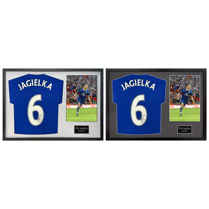 A professionally framed official Everton football shirt signed by Phil Jagielka, displayed with a crisp black mount inside a sleek wooden frame.