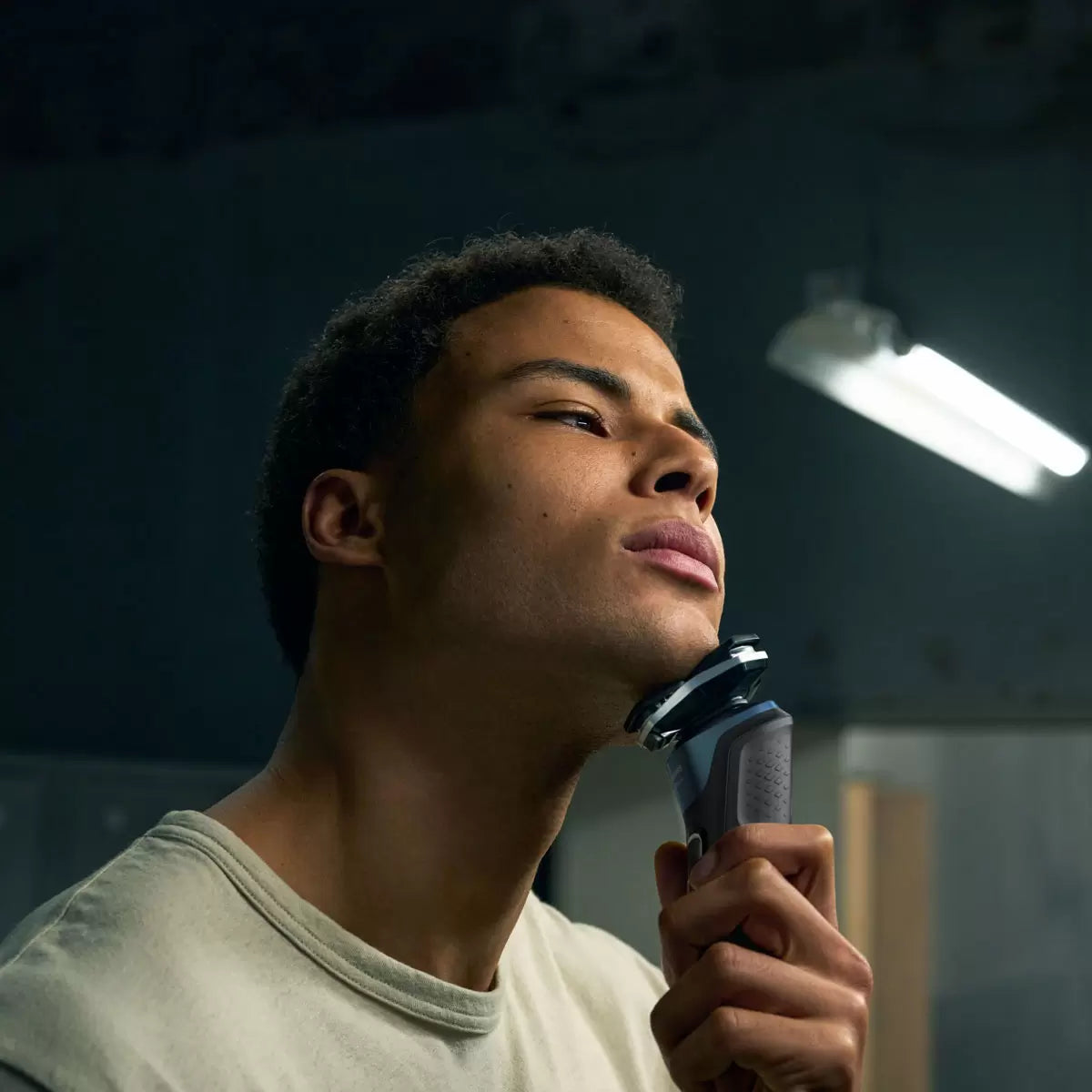 Side view of the Philips Series 5000 electric shaver with its LED display clearly visible, resting next to the included nose trimmer and travel case.
