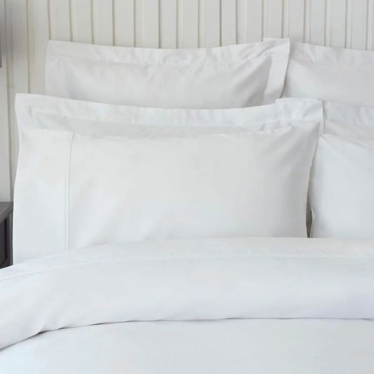 A pair of smooth, white Belledorm 450 thread count Pima cotton king-size pillowcases resting on a neatly dressed bed under soft morning light.
