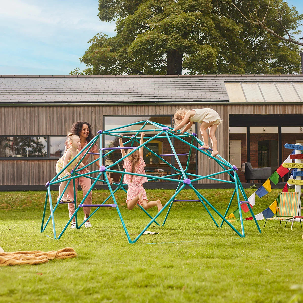 A blue and grey Plum Phobos Metal Climbing Dome installed on a green lawn for outdoor play.