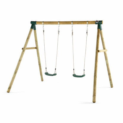 A Plum Ultimate premium wooden swing set standing in a lush green garden, featuring an assembled frame with a baby seat and trapeze attached, plus safety mats underneath.