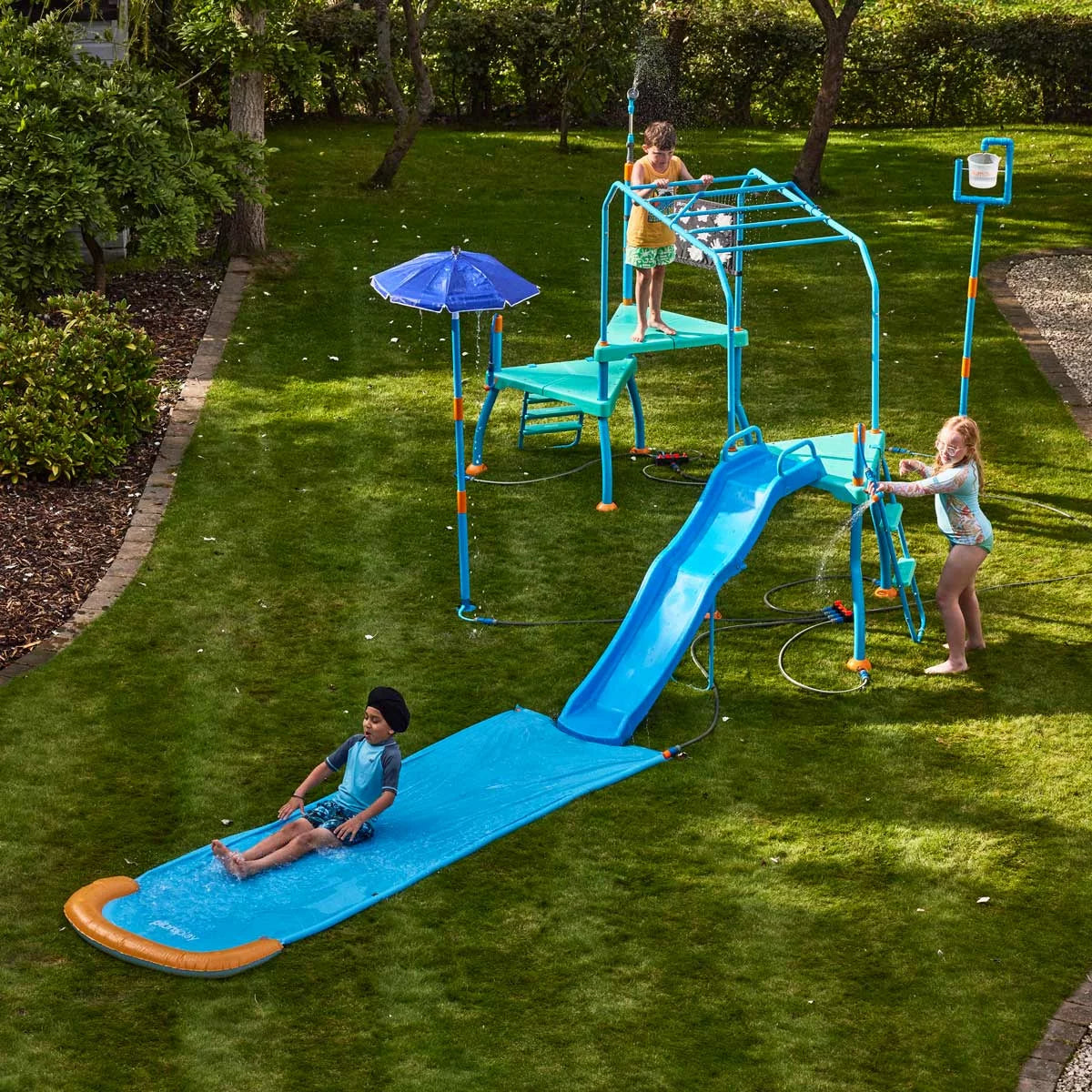 Plum Water Park Blaster Course blue outdoor play centre with climbing frame, water slide, sprinklers, monkey bars, and splash features installed in a garden for children's summer water fun-3