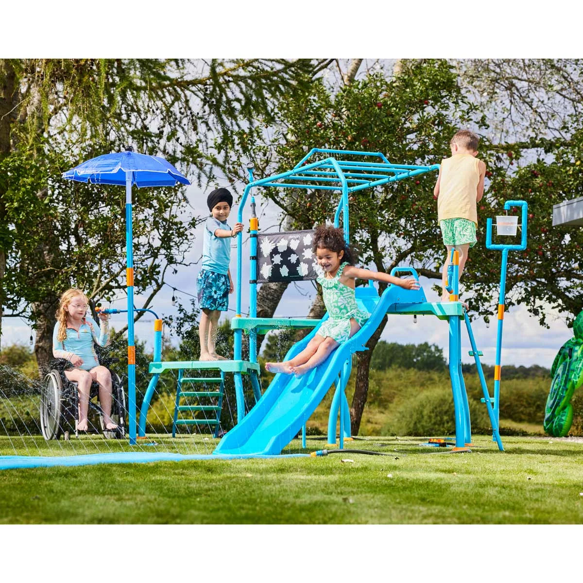 Plum Water Park Blaster Course blue outdoor play centre with climbing frame, water slide, sprinklers, monkey bars, and splash features installed in a garden for children's summer water fun.