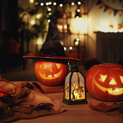 A portable black plastic Halloween handheld lantern glowing warmly with spooky pumpkin and skull pattern designs on a festive party table.