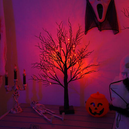 A pre-lit black birch tree with 24 warm LED lights glowing softly on an indoor mantelpiece decorated for Halloween