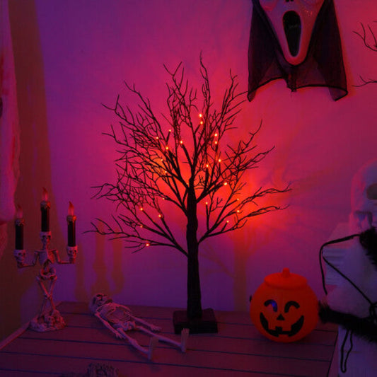 A pre-lit black birch tree with 24 warm LED lights glowing softly on an indoor mantelpiece decorated for Halloween