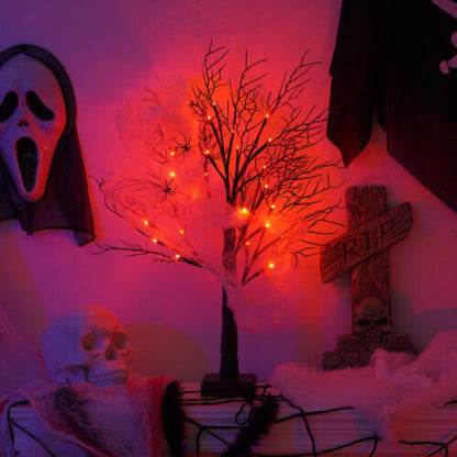 A pre-lit black birch tree with 24 warm LED lights glowing softly on an indoor mantelpiece decorated for Halloween
