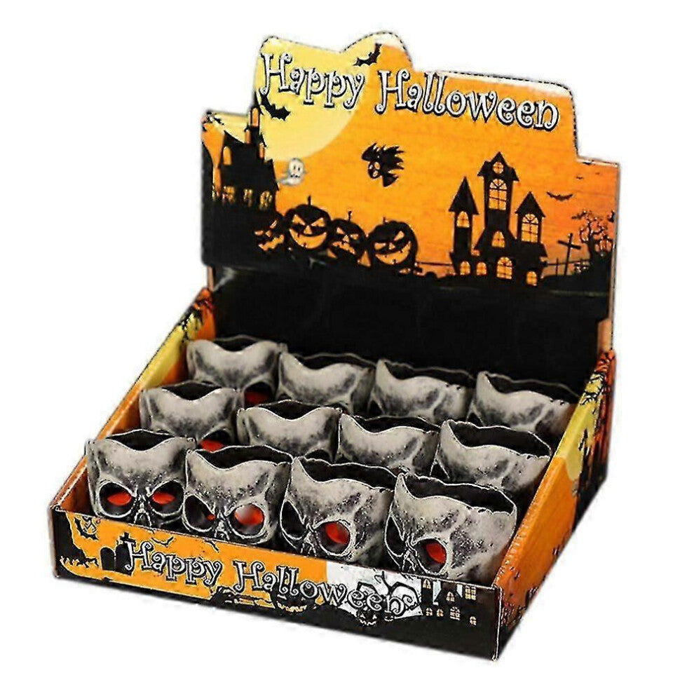 A 12-pack of mini pumpkin and skeleton LED battery-operated tea lights glowing warmly on a festive wooden party table.