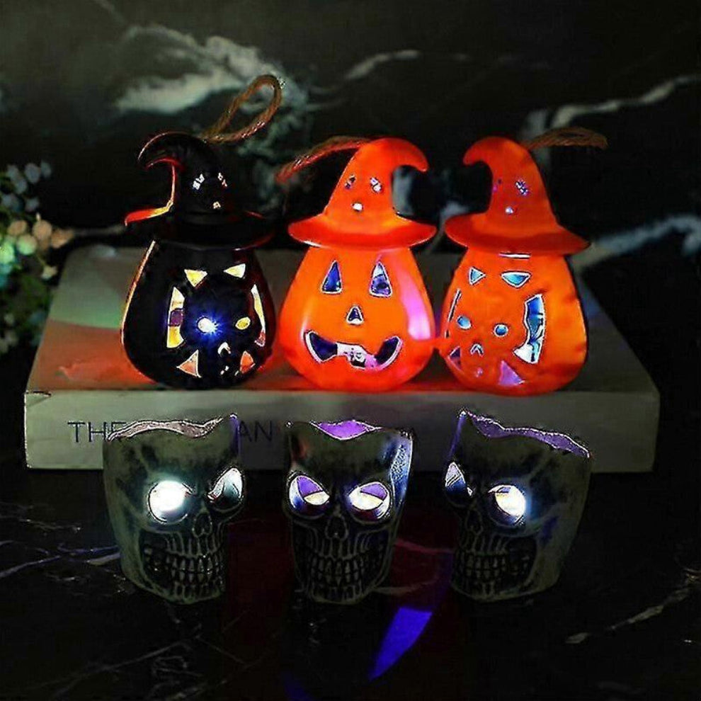 A 12-pack of mini pumpkin and skeleton LED battery-operated tea lights glowing warmly on a festive wooden party table.