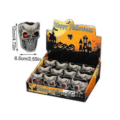 A 12-pack of mini pumpkin and skeleton LED battery-operated tea lights glowing warmly on a festive wooden party table.
