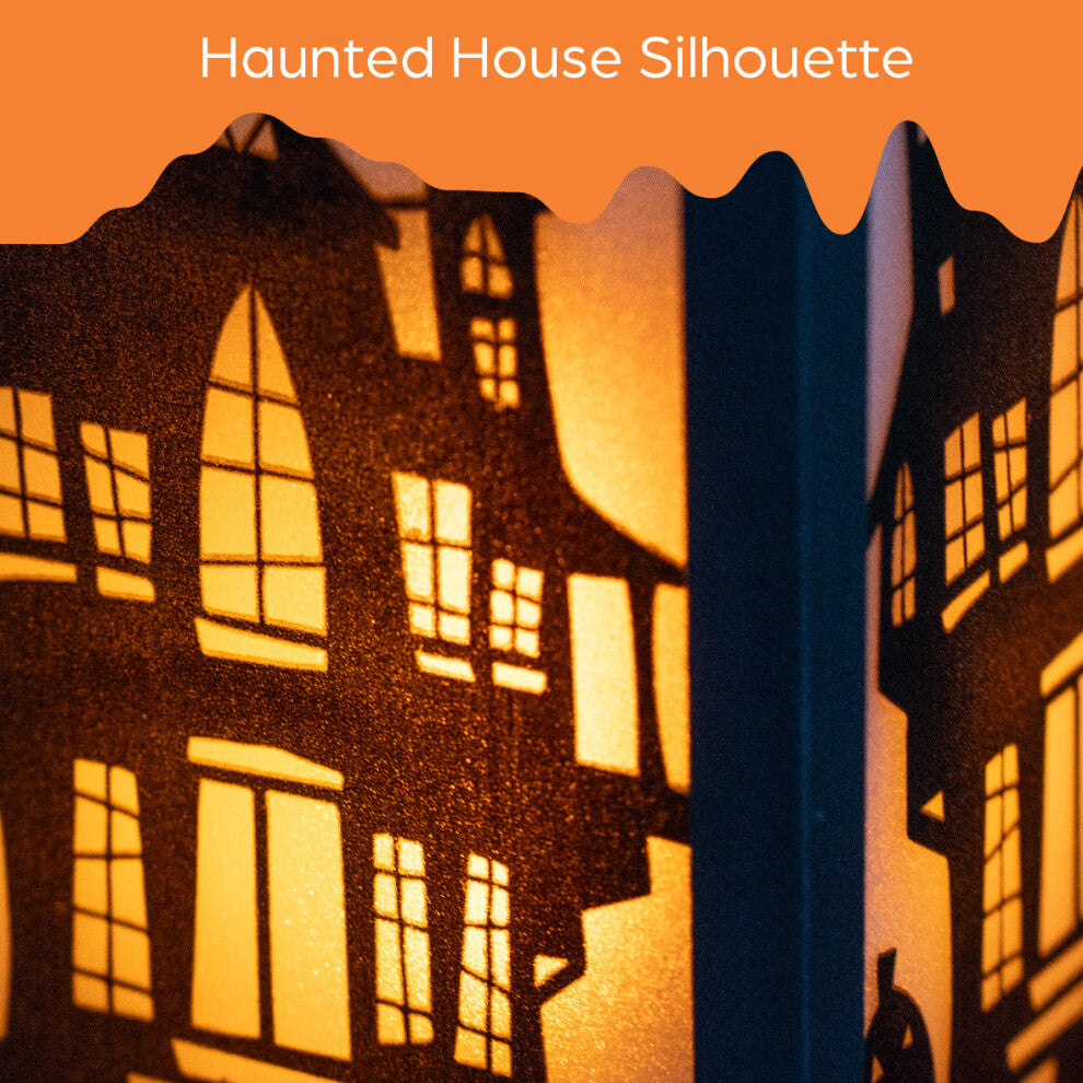 A 30.5cm black Victorian-style Global Gizmos LED Halloween lantern featuring a flickering orange candle effect and haunted house panels sitting on a wooden surface.