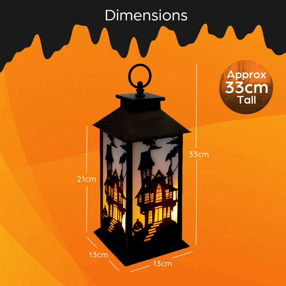 A 30.5cm black Victorian-style Global Gizmos LED Halloween lantern featuring a flickering orange candle effect and haunted house panels sitting on a wooden surface.