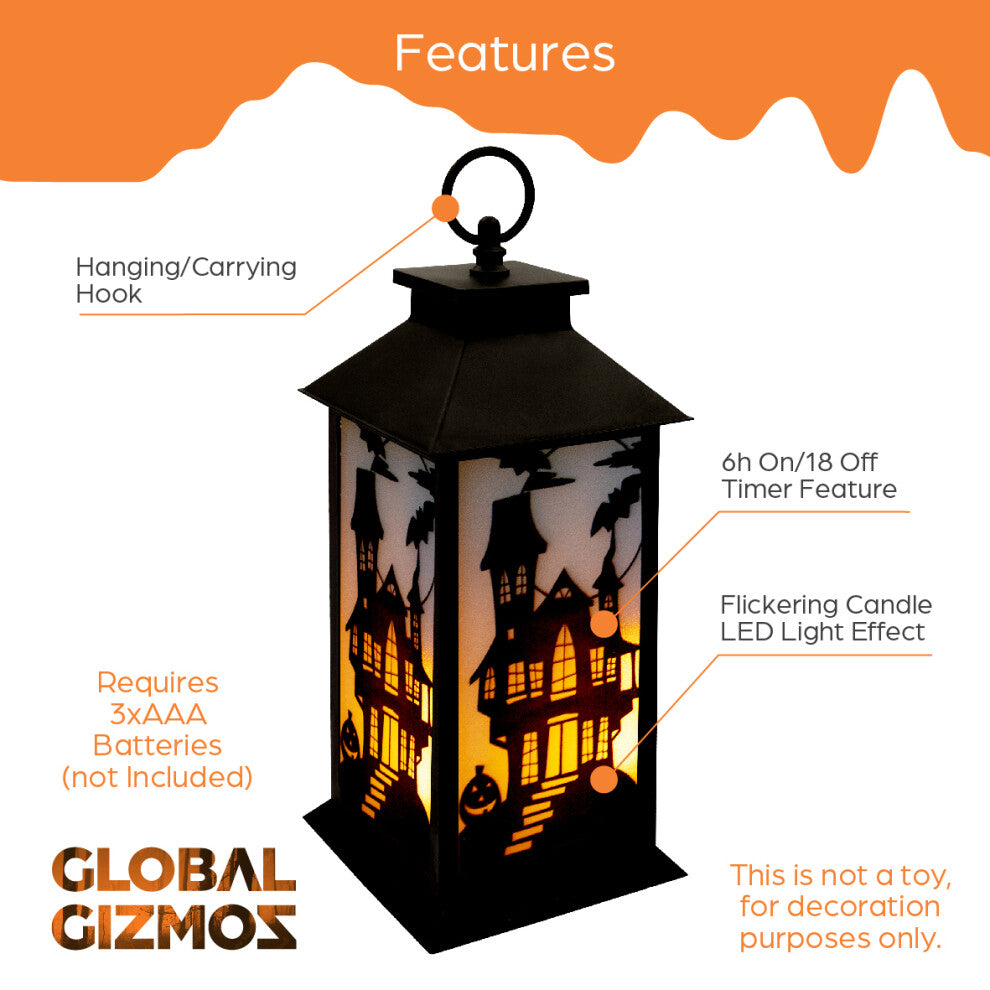 A 30.5cm black Victorian-style Global Gizmos LED Halloween lantern featuring a flickering orange candle effect and haunted house panels sitting on a wooden surface.