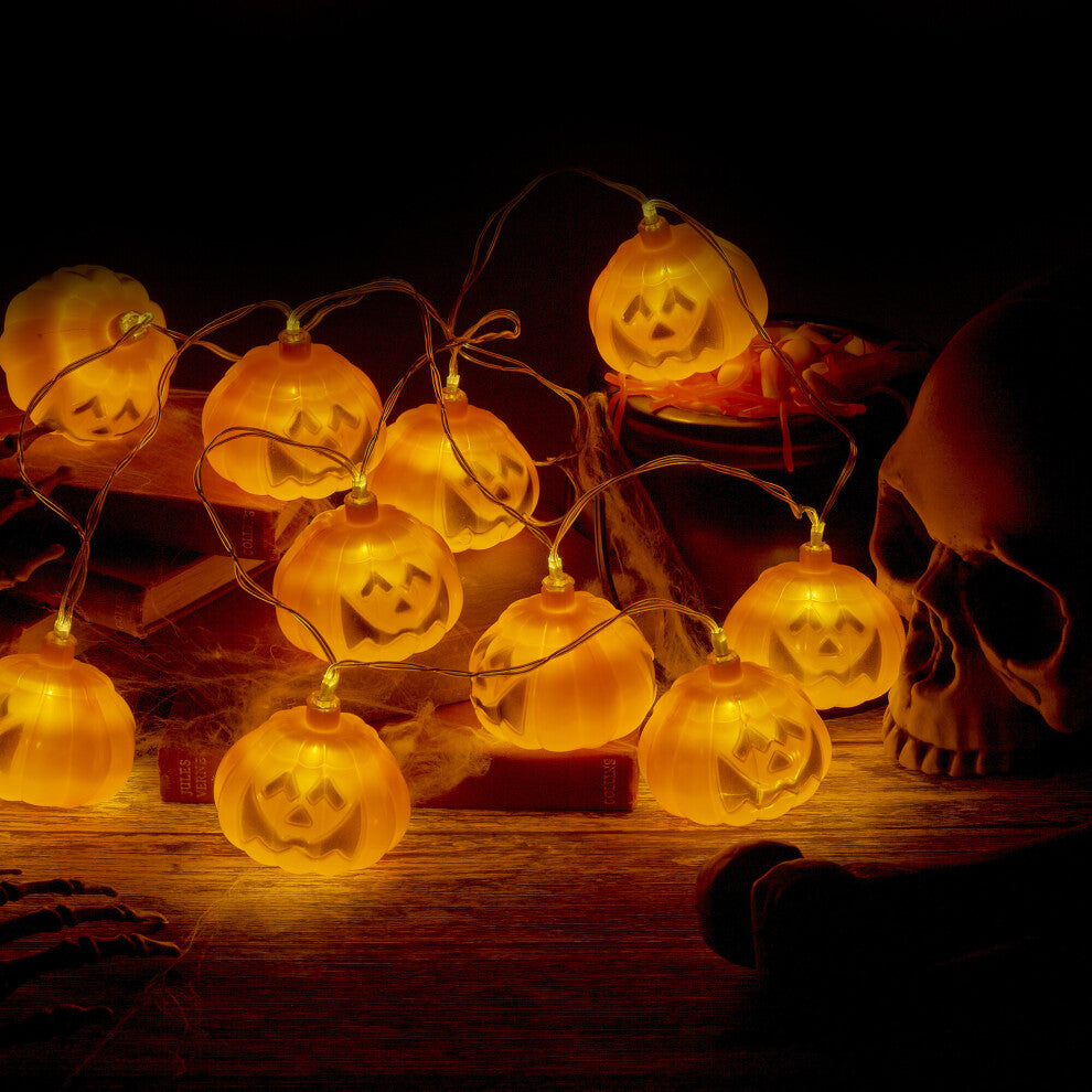 A 1.5-meter string of 10 pumpkin LED lights glowing warmly on a dark indoor party wall.
