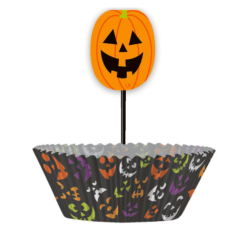 Pack of 24 orange paper cupcake cases featuring distinct spooky pumpkin face prints arranged on a wooden countertop next to freshly baked Halloween muffins.