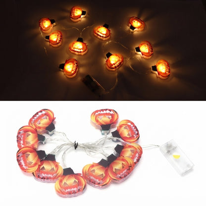 A strand of 10 cute LED pumpkin string lights glowing steadily along an outdoor garden patio fence.