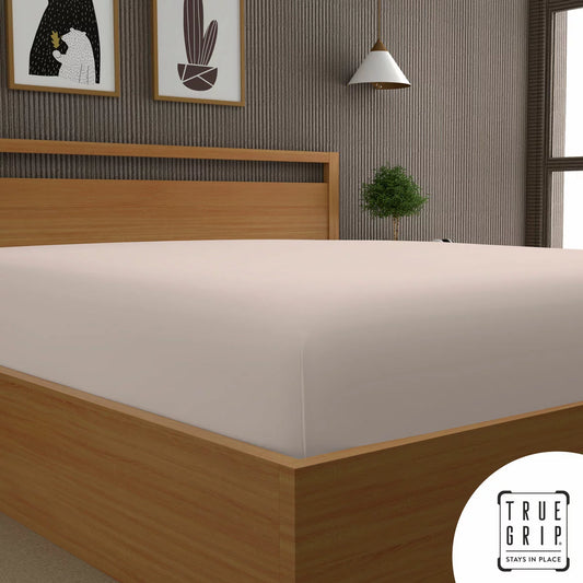 A single pink cotton sateen fitted sheet tightly secured over a thick mattress corner, demonstrating the snug fit of the True Grip elasticated base.