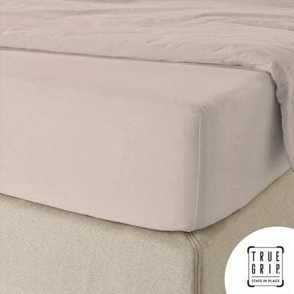 A single pink cotton sateen fitted sheet tightly secured over a thick mattress corner, demonstrating the snug fit of the True Grip elasticated base.