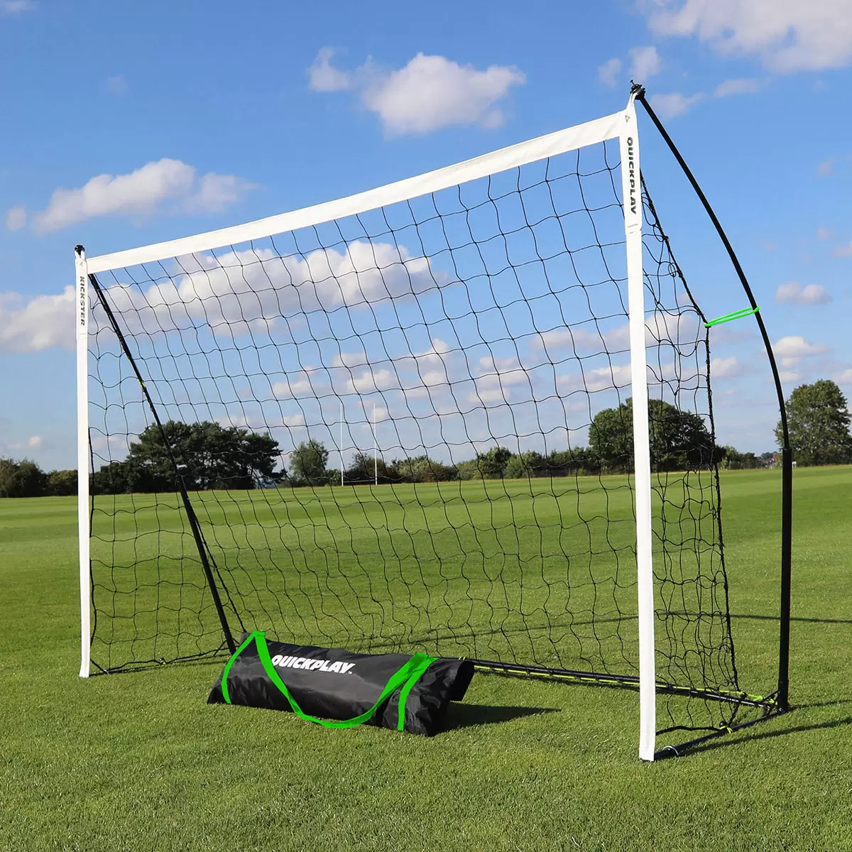 Complete Quickplay Kickster training kit set up on a manicured green grass pitch featuring the black and yellow frame goal, a Size 3 football, and bright orange mini cones spaced for agility drills.