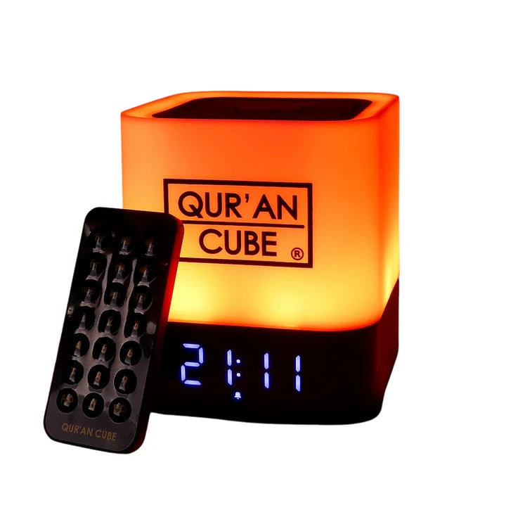 Studio shot of the rose gold Quran Cube LED X speaker glowing with a soft blue LED light on a bedside table displaying its digital clock face.