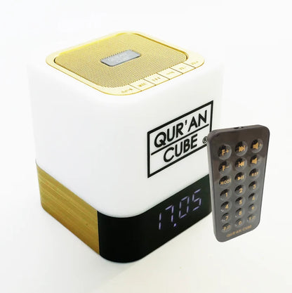Studio shot of the rose gold Quran Cube LED X speaker glowing with a soft blue LED light on a bedside table displaying its digital clock face.