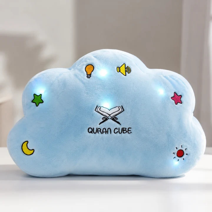 Soft yellow plush Quran Cube Dua Pillow showing stitched colorful button icons for Surahs and duas resting on a white bed sheet.
