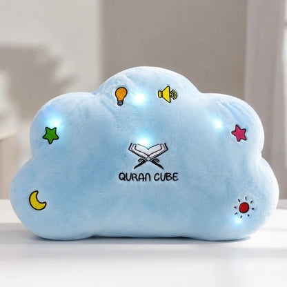 Soft yellow plush Quran Cube Dua Pillow showing stitched colorful button icons for Surahs and duas resting on a white bed sheet.