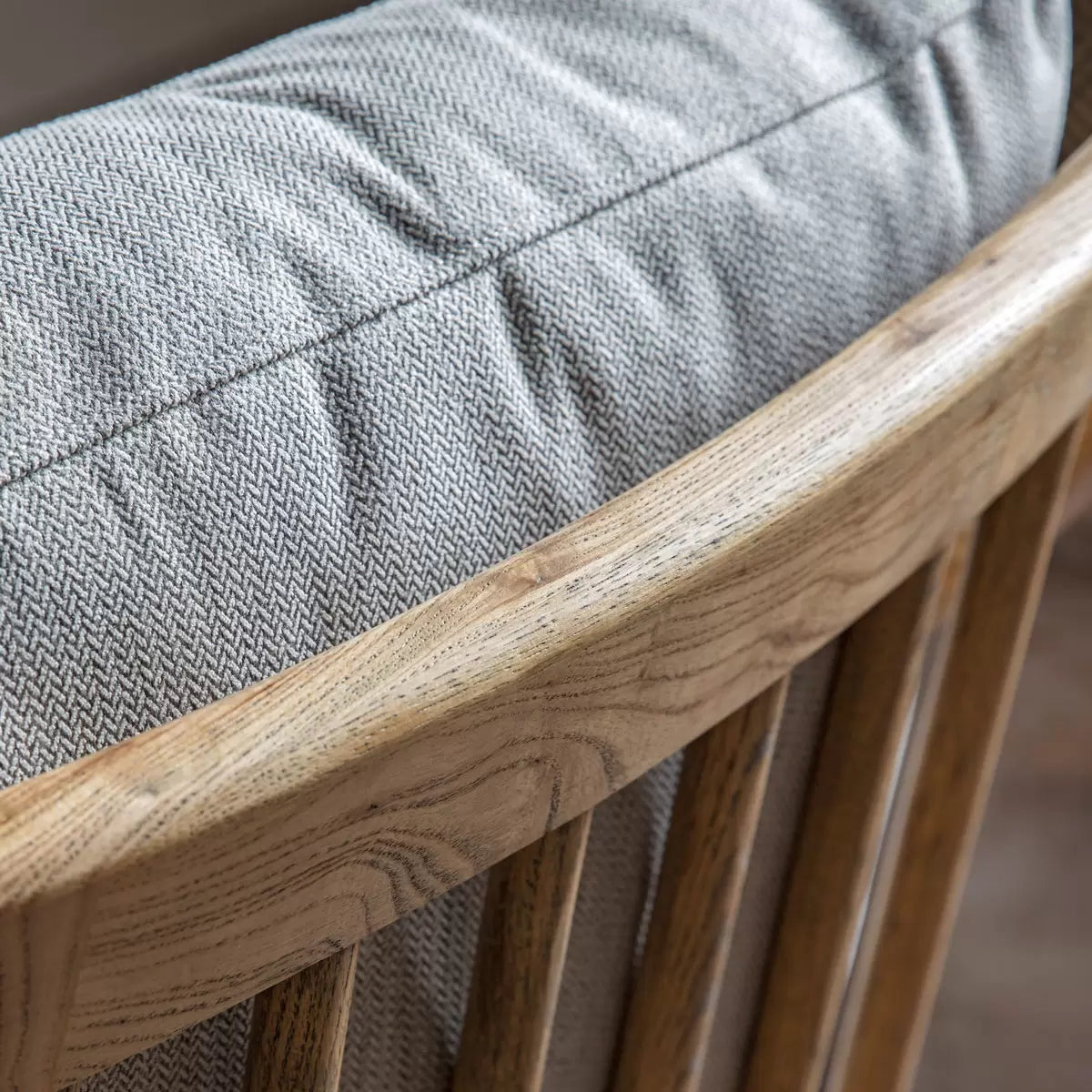 A side angle view of the Gallery Reliant natural linen armchair highlighting its exposed light-toned ash wood frame, padded natural linen upholstery, and retro silhouette.