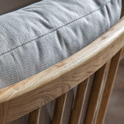 A side angle view of the Gallery Reliant natural linen armchair highlighting its exposed light-toned ash wood frame, padded natural linen upholstery, and retro silhouette.
