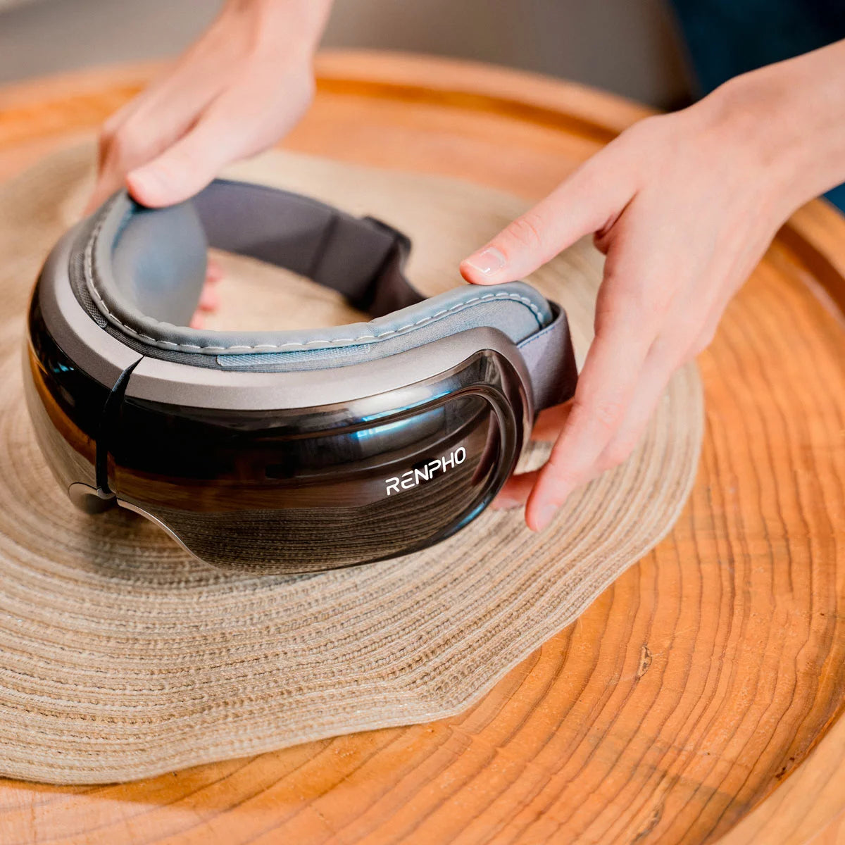 The Renpho Eyeris 3 eye massager in black, shown folded next to its storage bag, highlighting the sleek, foldable design and comfortable eye cushion.