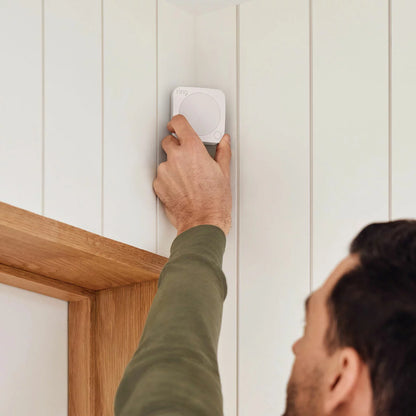 Flat lay arrangement of the white Ring 10 Piece Alarm 2nd Gen Starter Kit showing base station, keypad, indoor camera, contact sensors, motion detectors, and range extender against a neutral backdrop.